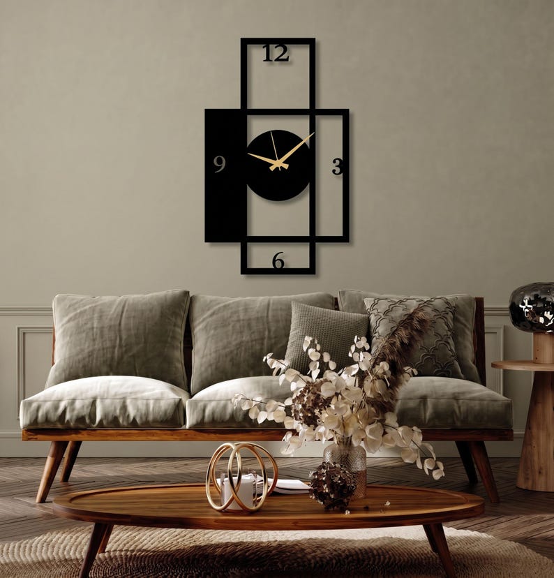 Pu&ograve; includere: Un orologio da parete nero con un design geometrico di cornici rettangolari sovrapposte. Il quadrante &egrave; un cerchio nero pieno con lancette dorate per ore e minuti. I numeri 12, 3, 6 e 9 sono posizionati all'interno della struttura.