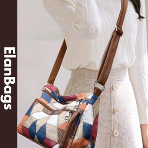 Puede incluir: Un bolso bandolera con un patrón de patchwork geométrico multicolor en tonos azul, naranja, blanco y rojo oscuro. El bolso tiene ribetes de piel sintética marrón, cremalleras metálicas plateadas y una correa ajustable. El texto dice ElanBags.