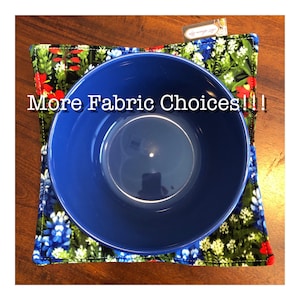 May include: A blue ceramic bowl sits atop a floral fabric bowl cozy. The cozy features a vibrant pattern of blue, red, and white flowers on a dark background. Text on the image reads "More Fabric Choices!!!"