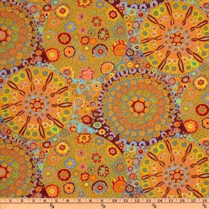 May include: A colorful fabric with a repeating pattern of large, circular floral designs in shades of orange, yellow, and blue. The design includes smaller floral and dot patterns on a dark brown background. The fabric is measured in inches.