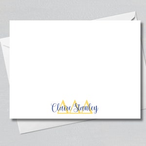 May include: White stationery card with a blue cursive name "Claire Stanley" and three yellow triangles.