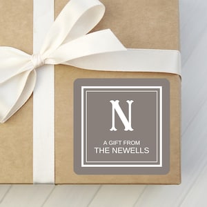 May include: A brown gift box with a white ribbon and a gray gift tag. The tag has a white letter "N" and the text "A gift from The Newells".