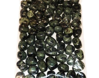 Puede incluir: Una bolsa de plástico transparente llena de numerosas piedras pulidas y rodadas en tonos verde bosque oscuro y negro. Cada piedra presenta una superficie lisa y brillante con patrones arremolinados únicos y texturas moteadas en todo.