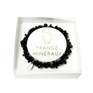 Puede incluir: Una pulsera hecha de pequeñas piedras negras pulidas dispuestas en forma circular. La pulsera cuenta con un pequeño dije de metal plateado y se presenta en una caja blanca con una etiqueta circular que dice FRANCE MINÉRAUX.