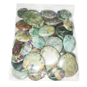 May include: A clear plastic bag filled with numerous polished, oval-shaped stones. The stones feature a mottled appearance with a mix of light green, teal, and cream colors, accented by distinct patches of deep magenta and dark brown mineral inclusions.