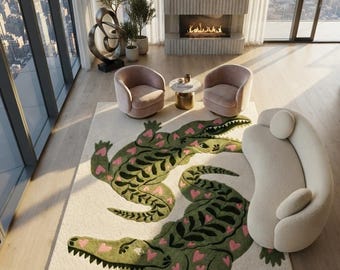 May include: A large rectangular area rug featuring a cream-colored background with two prominent green crocodile illustrations. The crocodiles are decorated with dark green leaf-like patterns and small pink heart shapes across their bodies.