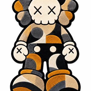 May include: A tufted rug shaped like a cartoon character with a skull-like head, X-shaped eyes, and gloved hands. The design features a geometric pattern in shades of black, cream, gray, and mustard yellow, outlined with a thick black border.