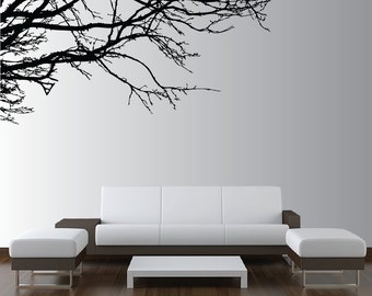 Könnte beinhalten: Ein weißes Sofa mit zwei weißen Hocker und einem weißen Couchtisch vor einer weißen Wand mit einer schwarzen Silhouette eines Baumzweigs.