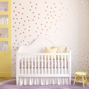 May include: A white crib with a white canopy and a white mattress. The crib is in a nursery with a yellow wall and a white wall with gold polka dots. There is a purple rug on the floor.