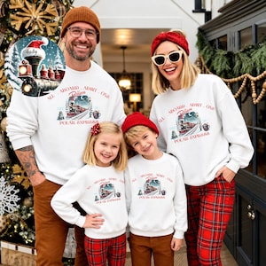 May include: Matching white crewneck sweatshirts featuring a graphic of a steam train, the text "ALL ABOARD, ADMIT ONE, Believe, POLAR EXPRESS", and a "DEC 25" date. The design includes a snowy landscape, a mug, and a Christmas tree.