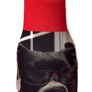 May include: A red and black bottle cooler with a photo of a dog wearing glasses. The dog has black and white fur and is looking at the camera.