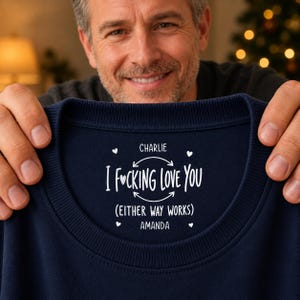 以下が含まれることがあります： ネイビーブルーのトレーナー。首元の内側に白い文字で「CHARLIE, I F*CKING LOVE YOU (EITHER WAY WORKS), AMANDA」とプリントされており、小さなハートのアイコンと反対方向を向いた2つの円形の矢印が添えられています。