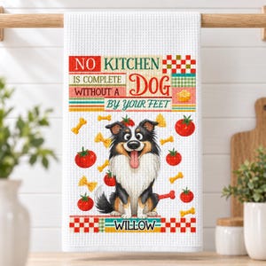 Könnte beinhalten: Ein weißes Küchentuch mit Waffelstruktur, das einen Cartoon-Hund mit schwarzem, weißem und hellbraunem Fell zeigt. Der Text lautet NO KITCHEN IS COMPLETE WITHOUT A DOG BY YOUR FEET und WILLOW. Das Design enthält rote Tomaten und gelbe Nudeln.