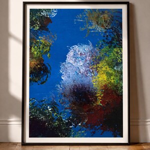May include: A framed abstract painting featuring a vibrant blue background with textured, layered brushstrokes in shades of yellow, green, deep red, and white. The composition creates a dense, organic appearance within a simple black frame.