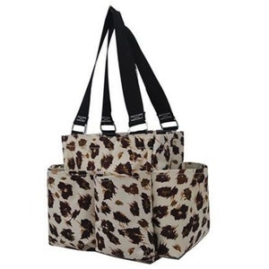 May include: A multi-pocket tote bag with a leopard print pattern. The bag features a cream-colored background with brown spots. It has black straps and silver metal hardware. The bag is designed with multiple compartments for organization.