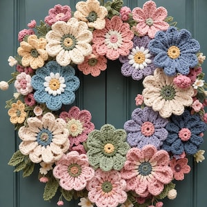 May include: A circular wreath constructed from various crocheted flowers in shades of pink, blue, cream, lavender, and sage green. The floral arrangement features layered petals and textured centers, accented with small crocheted leaves and buds.