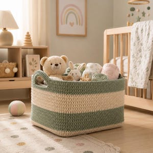 May include: A rectangular woven storage basket featuring horizontal stripes in sage green and cream. The basket has two integrated handles and is filled with various plush toys, including a tan teddy bear and a white rabbit, along with folded textiles.