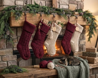 May include: Five knitted Christmas stockings in alternating burgundy and cream colors hang from a wooden mantel. The stockings feature ribbed cuffs and textured patterns. Two stockings have decorative tassels and wooden tags with text.