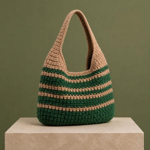 May include: A crochet hobo bag featuring horizontal stripes in alternating shades of tan and dark forest green. The bag is constructed with a textured stitch pattern and includes a single integrated shoulder strap at the top opening.