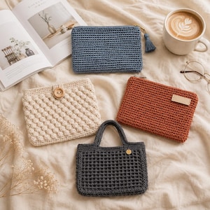 Peut inclure: Un ensemble de quatre articles crochetés : une pochette bleue zippée avec un pompon, une pochette crème avec une fermeture à bouton et un motif texturé, une pochette rouille zippée avec une étiquette rectangulaire et un mini sac cabas gris foncé.