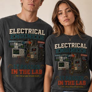 Könnte beinhalten: Ein anthrazitfarbenes Kurzarm-T-Shirt mit einem Grafikdruck mit dem Text "ELECTRICAL ENGINEER IT PASSED IN THE LAB THE FIELD HAD OTHER IDEAS" sowie Abbildungen von Laborgeräten, einem Oszilloskop und elektrischen Komponenten.