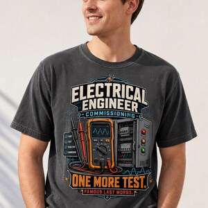 May include: A charcoal gray t-shirt featuring a graphic print of an electrical multimeter, a control panel, and the text "ELECTRICAL ENGINEER COMMISSIONING ONE MORE TEST. FAMOUS LAST WORDS." The design includes technical schematics and icons.