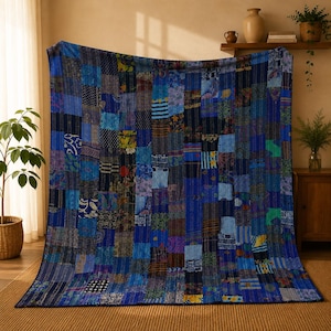 Op de afbeelding: Een rechthoekige patchwork quilt bestaande uit een verscheidenheid aan blauwe stoffen vierkanten met diverse patronen, waaronder bloemmotieven, geometrische vormen en strepen. De quilt is afgewerkt met zichtbare stikseldetails.