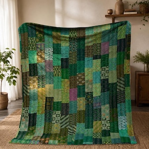 May include: A rectangular quilt featuring a patchwork design composed of vertical strips in various shades of green, teal, and olive. The fabric panels display diverse geometric and floral patterns, all joined by visible running stitch embroidery.