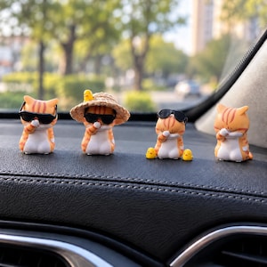 May include: Four small orange tabby cat figurines with white bellies. The first wears black sunglasses, the second wears a straw hat with a tiny yellow chick, the third wears black sunglasses with two tiny yellow chicks, and the fourth covers its eyes.