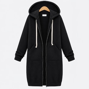 May include: A long-length black zip-up hoodie featuring a hood with thick white drawstrings, long sleeves with ribbed cuffs, and two front pockets. The garment is displayed on a wooden hanger and includes a central full-length metal zipper.