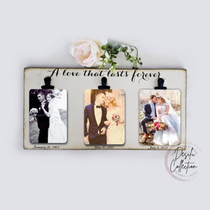 May include: A white wooden sign with the text "A love that lasts forever" and three black clips holding photos of a couple on their wedding day. The photos are dated January 16, 1965, July 16, 1983, and July 9, 2022.