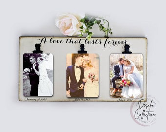 May include: A white wooden sign with the text "A love that lasts forever" and three black clips holding photos of a couple on their wedding day. The photos are dated January 16, 1965, July 16, 1983, and July 9, 2022.
