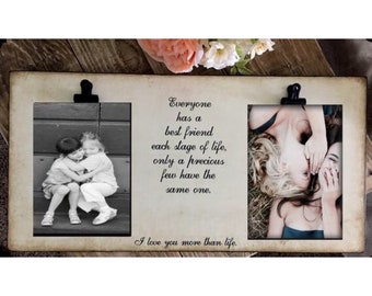 Op de afbeelding: Een dubbele fotolijst met een witte achtergrond en een zwart-witfoto van twee jonge meisjes die elkaar omhelzen in het linker frame en een kleurenfoto van twee jonge vrouwen die elkaar omhelzen in het rechter frame. De lijst heeft een citaat dat luidt: "Iedereen heeft in elke fase van het leven een beste vriend, maar slechts weinigen hebben dezelfde. Ik hou meer van je dan van het leven."