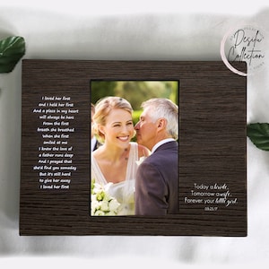 May include: A dark brown wooden picture frame with a photograph of a bride and her father. The frame includes the text "I loved her first" and "Today a bride, tomorrow a wife, forever your little girl."