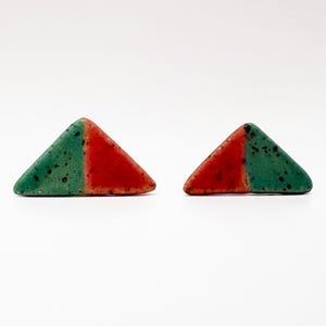 Può includere: Un paio di orecchini a lobo triangolari caratterizzati da un design diviso, con una metà in smalto verde acqua maculato e l'altra metà in smalto rosso pieno. Gli orecchini presentano una finitura liscia e arrotondata.