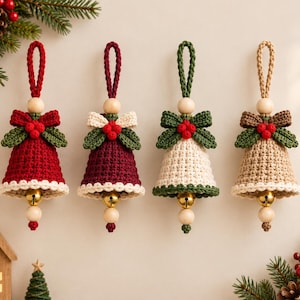 Puede incluir: Cuatro adornos de campana de ganchillo con un lazo para colgar, una cuenta de madera, un lazo con tres bayas rojas y un cascabel metálico en la base. Las campanas son de color rojo, granate, crema y beige, con un borde de ganchillo en contraste.