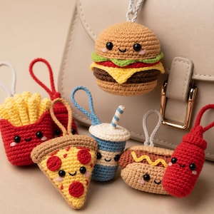 May include: A collection of six crocheted food-themed keychains featuring a hamburger, french fries, a pizza slice, a drink cup with a straw, a hot dog, and a ketchup bottle. Each item has a small loop for attachment and a smiling face.