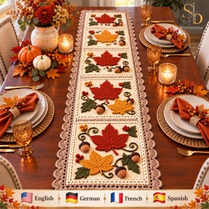 Peut inclure: Un chemin de table rectangulaire en crochet avec une base couleur crème et une bordure festonnée. Le chemin est décoré de motifs automnaux appliqués, notamment des feuilles d'érable rouges et jaunes, du feuillage vert et des glands.