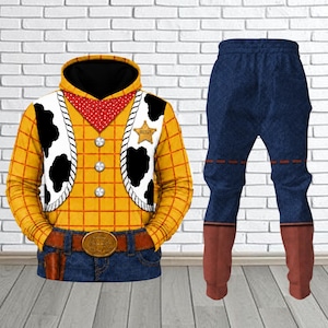 Könnte beinhalten: Ein Set aus einem langärmeligen Kapuzenpullover und passender Hose mit gelbem Karomuster, einer weißen Weste mit schwarzen Kuhflecken, einem roten Halstuch, einem goldenen Sheriffstern und einer Hose in blauer Denim-Optik.