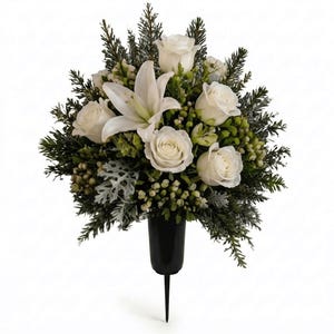 May include: A floral arrangement featuring white roses and a central white lily, accented with green pine needles, dusty miller foliage, and small light green berries. The flowers are held in a black, tapered, pointed-base cemetery vase.