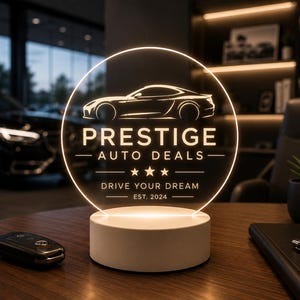 May include: A circular LED sign with a white light base featuring a car silhouette and the text PRESTIGE AUTO DEALS, three stars, the phrase DRIVE YOUR DREAM, and EST. 2024. The sign is illuminated, displaying clear white lettering and graphics.