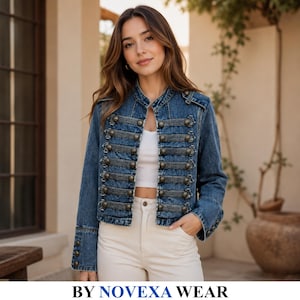 Peut inclure: Une veste en jean bleu dotée d'un col officier, de manches longues avec poignets boutonnés et d'un devant d'inspiration militaire avec des bandes de tissu sombres horizontales et des boutons métalliques, portée sur un haut et un pantalon blancs.