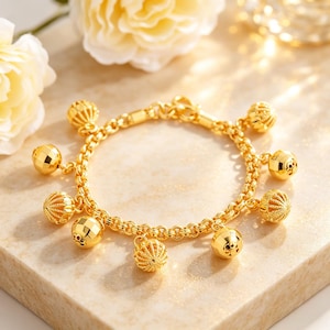 May include: A gold chain bracelet featuring a series of dangling spherical charms. The charms alternate between smooth, polished surfaces and textured, ribbed designs. The bracelet is constructed with circular links and a secure clasp mechanism.