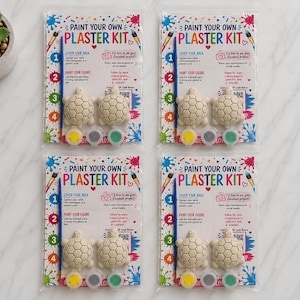 May include: Four identical Paint Your Own Plaster Kit sets in clear plastic packaging. Each kit includes two unpainted plaster turtle figures, a blue paintbrush, and three small circular paint pots in yellow, gray, and green colors.