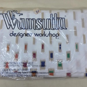May include: A Wamsutta Designer Workshop queen flat sheet in white with a pattern of vertical tan dashes and small, colorful rectangular accents. The packaging states it is No Iron Ultracale, 50% Fortrel polyester and 50% cotton, for a 60x80 inch mattress.