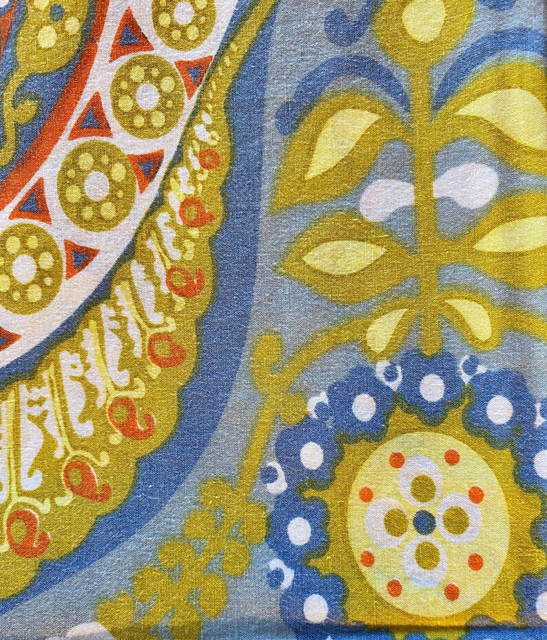 May include: A fabric with a blue, yellow, and orange paisley pattern. The fabric has a repeating pattern of leaves, flowers, and circles.