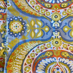 May include: A close-up of a fabric with a blue, green, yellow, orange, and white paisley pattern.