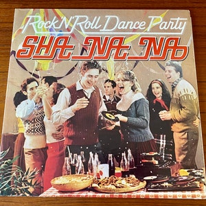 May include: A vintage record album cover featuring a group of people dancing at a party. The album cover is titled "Rock 'N' Roll Dance Party" with the band name "SHA NA NA" in large red letters. The album cover features a colorful background with balloons and confetti.