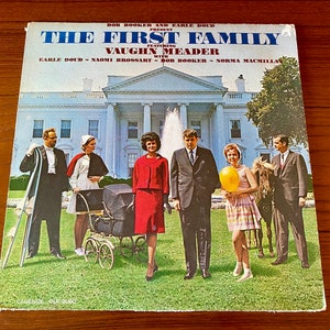 May include: A vintage record album cover featuring a photo of a group of people dressed in 1960s attire standing in front of the White House. The album title is "The First Family" featuring Vaughn Meader with Earle Doud, Naomi Brossart, Bob Booker, and Norma MacMillan. The album cover is in the style of a parody of the Kennedy family.