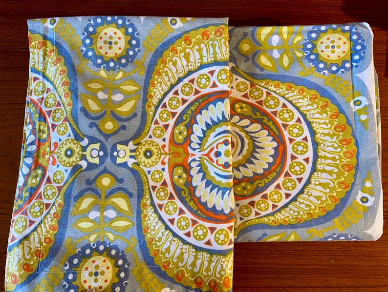 May include: Two fabric panels with a blue, green, yellow, orange, and white paisley pattern. The panels are sewn together along the top edge.